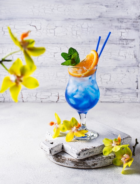 Blaues Cocktailgetränk mit Eis und Orange