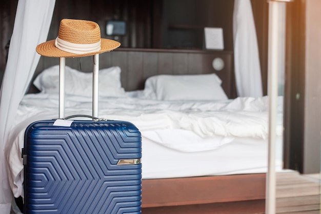 Blaues Gepäck mit Hut im modernen Hotelzimmer nach Türöffnung. Reisezeit, Service, Reise, Reise, Sommerurlaub und Urlaubskonzepte