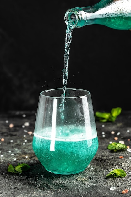 Blaues Getränk mit niedrigem Alkoholgehalt gekühlte bunte Getränke auf rustikalem schwarzem Hintergrund Sommerfest Konzept für alkoholische Getränke Freeze Motion Drops in Liquid Splash