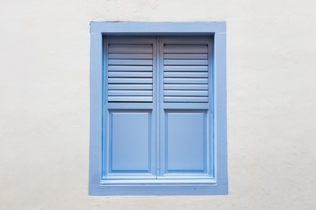 Blaues hölzernes Fenster ist klassische Weinleseart auf Weißzementwandhintergrund.