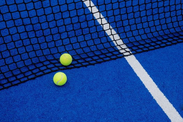 Blaues künstliches Gras Paddel Tennisplatz zwei Bälle in der Nähe des Netzes