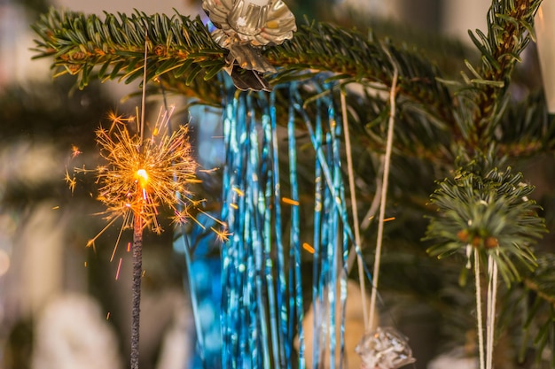 Blaues Lametta und eine brennende Wunderkerze mit vielen Funken zu Weihnachten