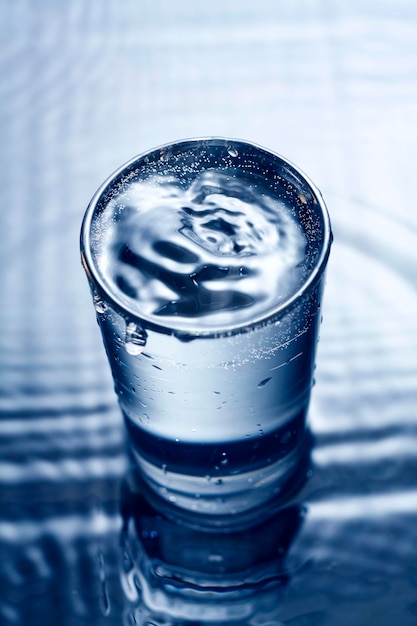 Blaues monochromes Bild von spritzendem Wasser in einem Glas