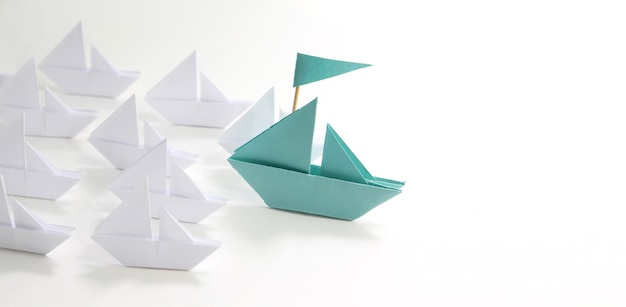 blaues Papierschiff mit kleinen Booten. Führungskonzept.