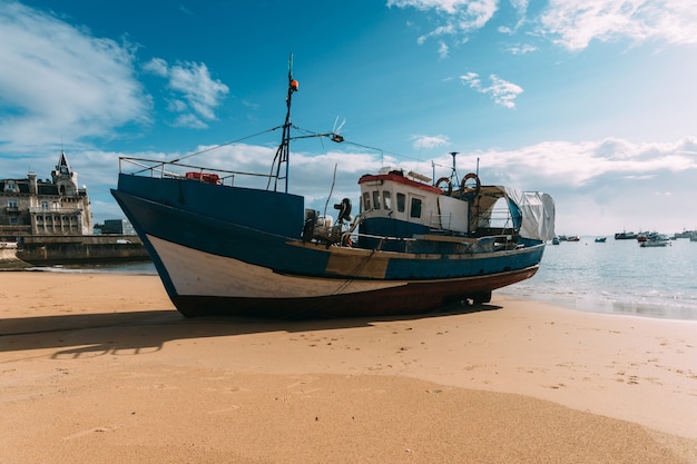 Blaues Schiff am Strand unter bewölktem Himmel in Cascais Portugal