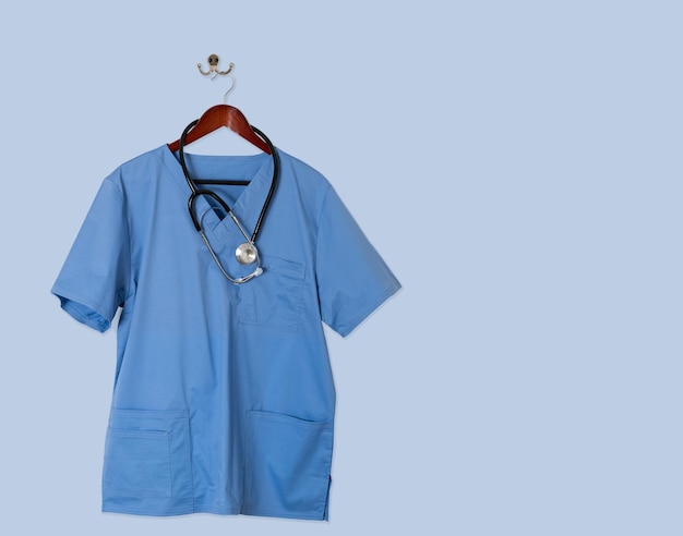 Blaues Scrubs-Hemd für medizinische Fachleute, das an der blauen Wand hängt