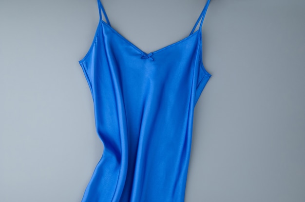 Blaues weibliches Nachthemd auf grauem Hintergrund, isoliert, Ansicht von oben