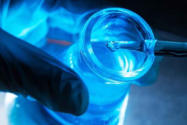 blaues Wissenschaftsreagenzglas, Flasche in der Hand des Wissenschaftlers mit einem Tropfen chemischer Flüssigkeit im Reagenzglas Wissenschaft
