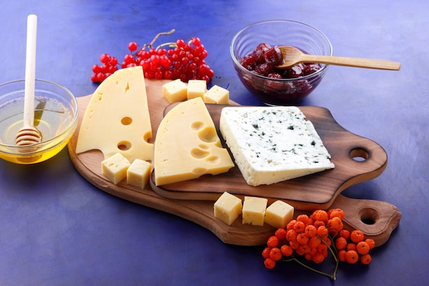 Blauschimmelkäse und gelber Hartkäse mit Früchten und Beeren auf Holzbrettern Verschiedene Käsesorten mit Honig auf blauem Hintergrund Nahaufnahme