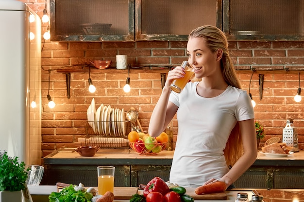 Bleib ruhig, iss Obst und Gemüse, glückliche junge Frau, die Gemüse in der modernen Küche gemütlich kocht