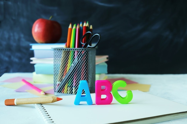 Bleistifte bunte Buchstaben Stapel Bücher und Apfel auf Schultafel Hintergrund zurück zur Schule