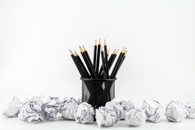 Bleistifte im Korb und in zerknittertem Papierball auf einer weißen Tabelle. - Arbeits- und Geschäftsideenkonzept.