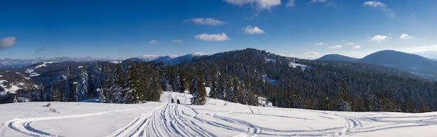 Blick auf das atemberaubende Winterpanorama der verschneiten Hänge und Hügel zwischen den üppigen weißen Wolken. Das Konzept der betörenden harten Winternatur