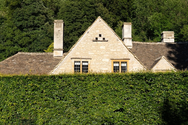 Blick auf das Hausdach hinter der grünen Hecke Cotswolds England UK