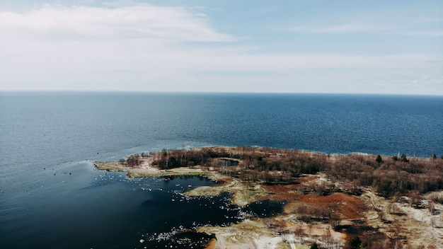 Blick auf das Meer von Quadcopter, Sand und Felsen an der Seeküste. Ozeanufer-Draufsicht. Horizont und blaues Wasser.