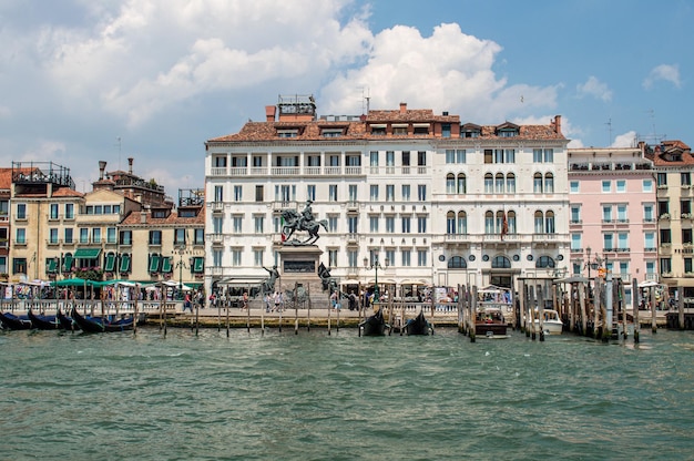 Blick auf den Damm des Venedig-Kanals an einem warmen Sommertag, mit schwimmenden Booten und alten Häusern, Venedig