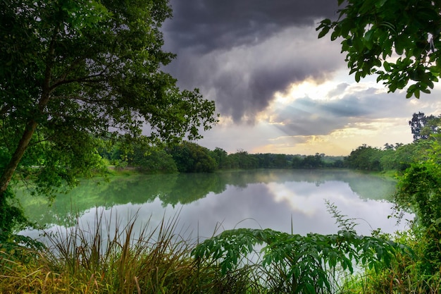 Blick auf den farbenfrohen dramatischen Himmelssonnenuntergang oder -aufgang mit Wolkenhintergrund auf dem Wasserfluss im Wald, Himmel mit Wolken in der Natur und Reisekonzept.