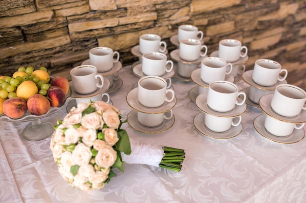 Foto blick auf den gedeckten tisch mit teetassen und hochzeitsstrauß