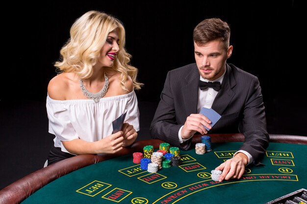 Blick auf den jungen, selbstbewussten Mann mit der Dame, während er Poker spielt.