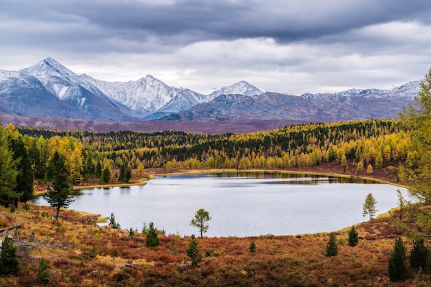 Blick auf den Kidelu-See und die schneebedeckten Gipfel des Kurai-Kamms. Herbstliche Berglandschaft. Altai, Russland