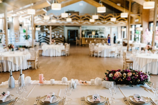 Blick auf den Restaurantsaal Festlich gedeckter Tisch Komposition aus Blumen Grün Kerzen im Hochzeitsbankettsaal Tisch Jungvermählten mit Tischdecke bedeckt, serviert mit Geschirr Besteck Close up