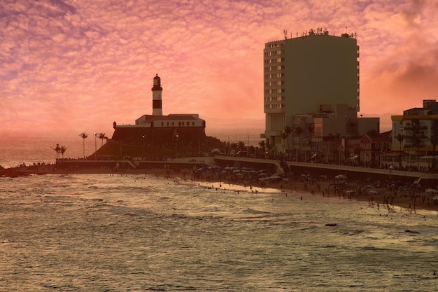 Blick auf den Sonnenuntergang an der Strandbar mit dem Leuchtturm von Barra im Hintergrund