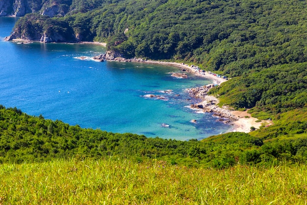 Blick auf den Strand mit türkisfarbenem Wasser und grünen Hügeln im Fernen Osten Russlands