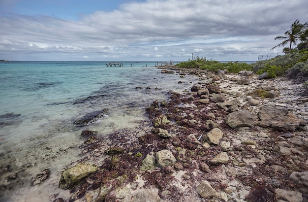 Blick auf den Strand von Xpu-Ha in Mexiko mit seiner Klippe unter einem Himmel, der von Wolken bedeckt ist, die Regen versprechen.