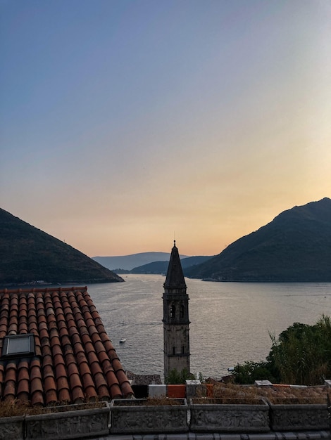 Blick auf die Bucht von Kotor bei Sonnenuntergang mit Bergen, Turm und Dächern