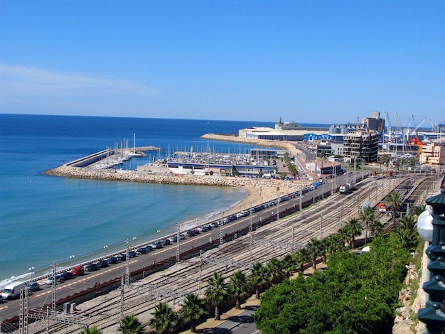 Blick auf die Küste von Tarragona von oben, Meer, Bahngleise und ein großer Hafen, Spanien