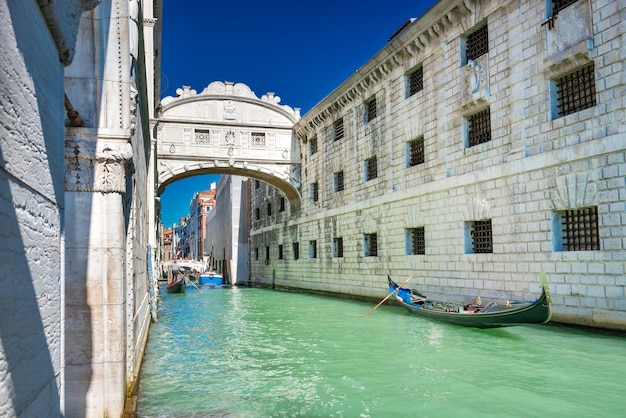 Blick auf die Seufzerbrücke über den Kanal mit Gondeln in der Nähe des Dogenpalastes in Venedig, Italien