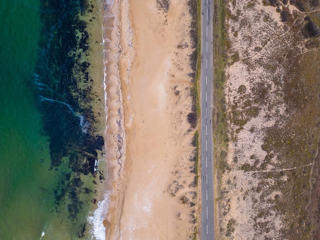 Blick auf die Straße entlang der sandigen Küste von den Drohnenautos, die auf der Straße entlang des Meeres fahren