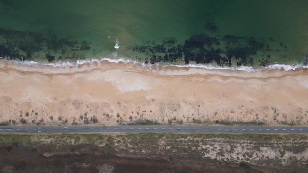 Blick auf die Straße entlang der sandigen Küste von der Drohne, die über leere Straße und Strand fliegt