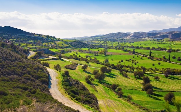 Blick auf die wunderschöne Landschaft mit frischen grünen Wiesen und Berggipfeln an einem sonnigen Tag mit blauem Himmel und Wolken im Frühling.