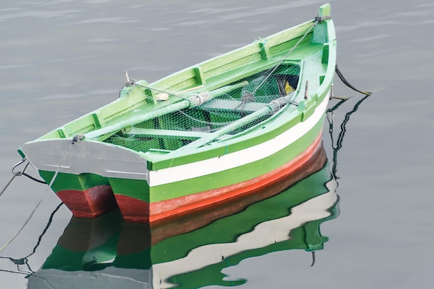 Blick auf ein Fischerboot, das sich in einem ruhigen Meer widerspiegelt