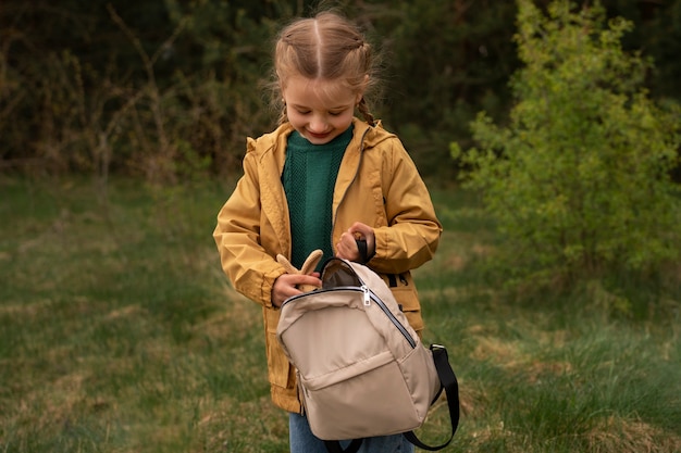 Foto blick auf ein kleines mädchen mit rucksack, das in der natur unterwegs ist