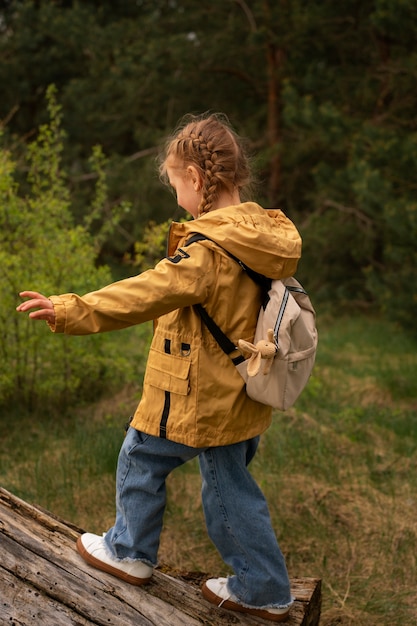 Foto blick auf ein kleines mädchen mit rucksack, das in der natur unterwegs ist