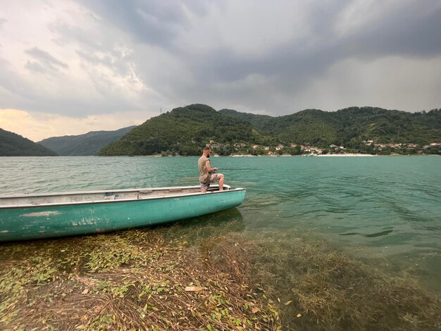 Blick auf ein Meer und die Berge und einen Mann, der auf dem Boot in Bosnien und Herzegowina steht