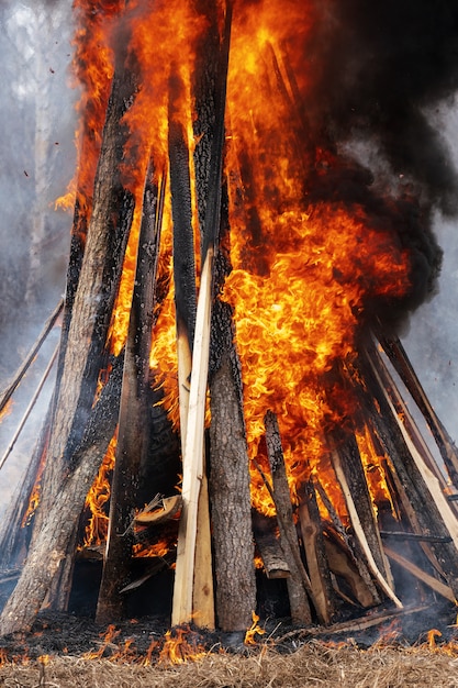 Blick auf ein riesiges Lagerfeuer aus Holzbrettern und Autoreifen, eine starke Flamme aus rotem Feuer, die schwarzen Rauch in den Himmel kräuselt.