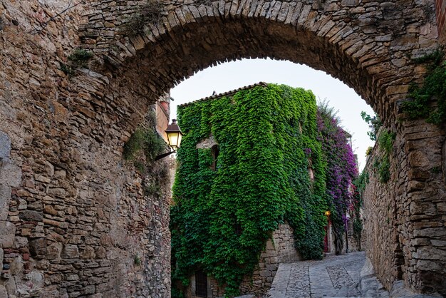Blick auf eine blühende Straße im mittelalterlichen Dorf Peratallada in Girona, Katalonien, Spanien.
