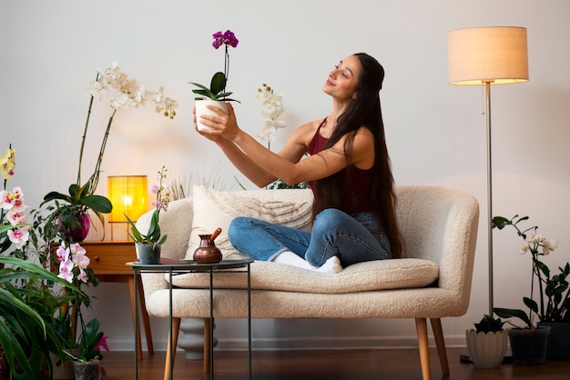 Foto blick auf eine frau, die ihr zuhause mit orchideeblumen schmückt