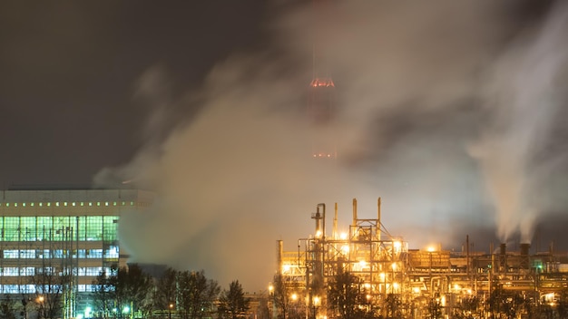 Blick auf eine große Fabrik oder Anlage im Licht der Nachtbeleuchtung Aus den Schornsteinen der Fabrik kommt viel Rauch Umweltverschmutzung Brand in einer Abfallverwertungsanlage