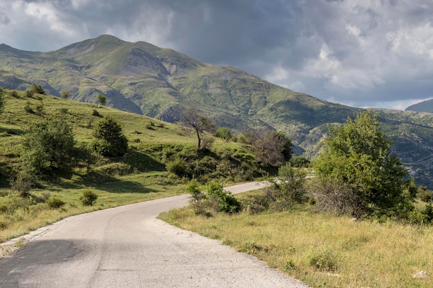 Blick auf eine ländliche Straße und die Berge in einer sommerlich bewölkten Tagesregion Tzoumerka Griechenland Berge Pindos