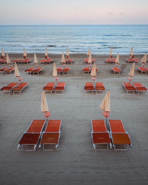 Foto blick auf einen meerestrand mit roten liegestühlen und sonnenschirmen ligurische see laigueglia italien