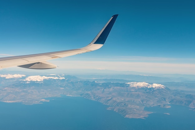 Blick auf einen schneebedeckten Berg aus einem Fenster im Flugzeug.