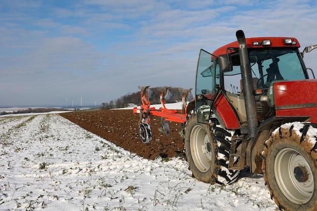 Blick auf einen Traktor bei der Arbeit, der im Winter ein Feld pflügt