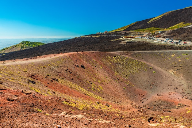 Blick auf einen Vulkankrater mit buntem Lavasand und Steinen. Panoramablick auf den Ätna, Sizilien, Italien