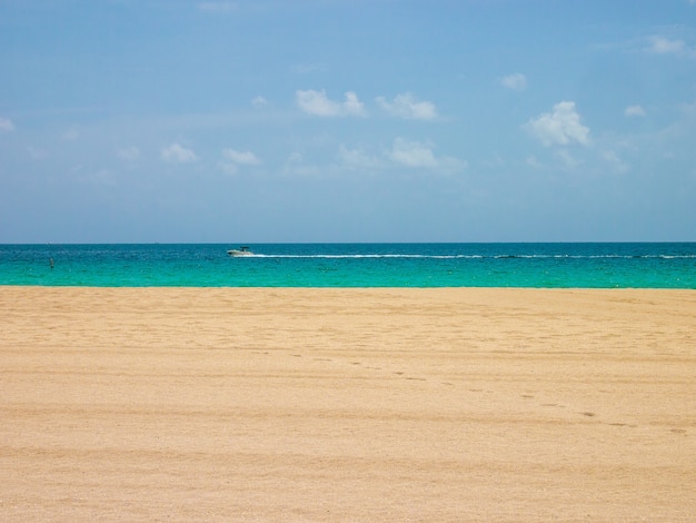 Blick auf Himmel, Meer und Sand am Miami Beach im Sommer mit einem vorbeifahrenden Schnellboot.