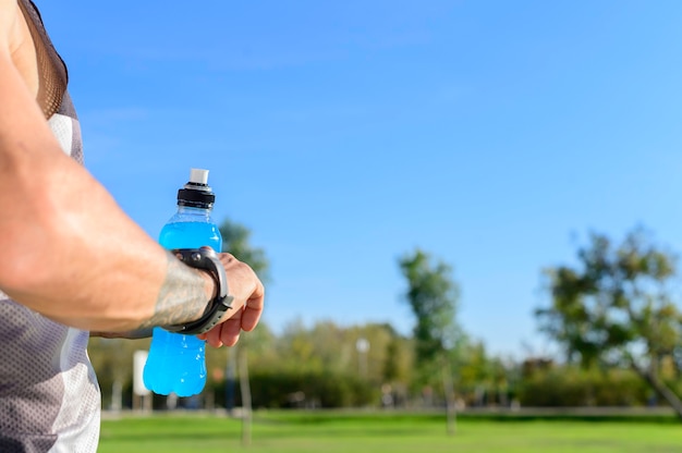 Blick auf intelligente Sportuhr im Park mit isotonischem Getränk