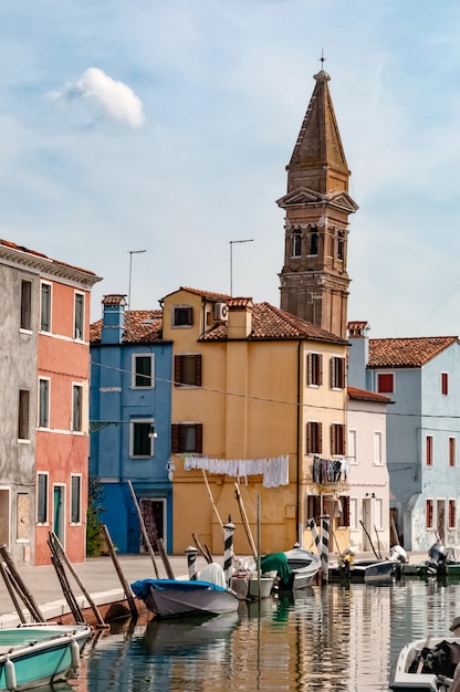 Blick auf leere Straße mit Booten im Wasserkanal, typischen bunten Häusern und altem Turm in Burano-Insel, Italien